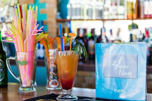 a table with three glasses of drinks and a blue bag at Zante Nest Studios & Apartments in Alikanas