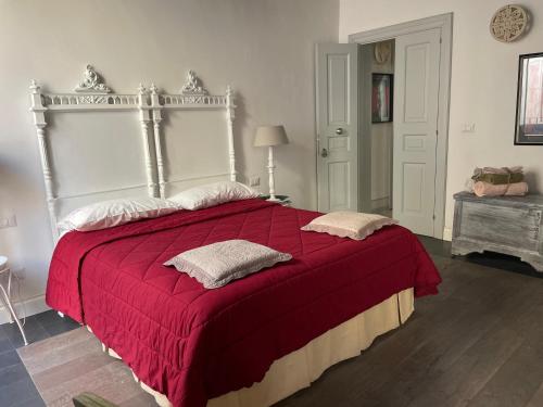 a bedroom with a large bed with a red blanket at Palazzo Siena De Facendis in Bitonto
