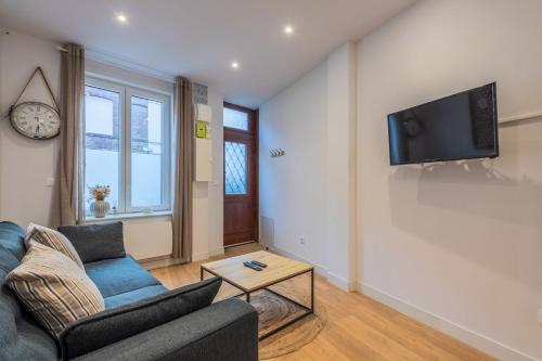 un salon avec un canapé et une télévision sur un mur dans l'établissement Maison 2 chambres atypique, avec cour, à La Madeleine