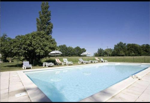 une grande piscine avec chaises et parasols dans l'établissement Propriété en pleine nature,grands espaces,, Périgord Noir, piscine chauffée, climatisation,wifi, à Saint-Pardoux-et-Vielvic