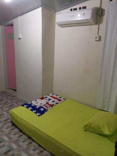 a bedroom with a green bed in a room at Air Manis Secret Surfcamp in Taluk Batung