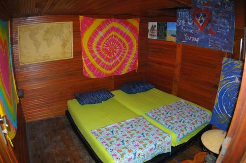a small bed in a room with wooden walls at Air Manis Secret Surfcamp in Taluk Batung