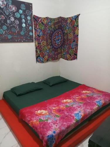 a bed with a colorful comforter on a wall at Air Manis Secret Surfcamp in Taluk Batung