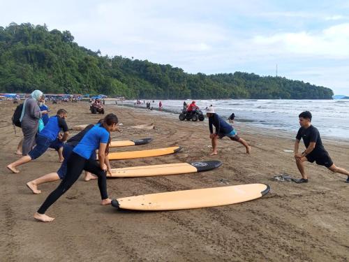 a group of people on a beach with surfboards at Air Manis Secret Surfcamp in Taluk Batung