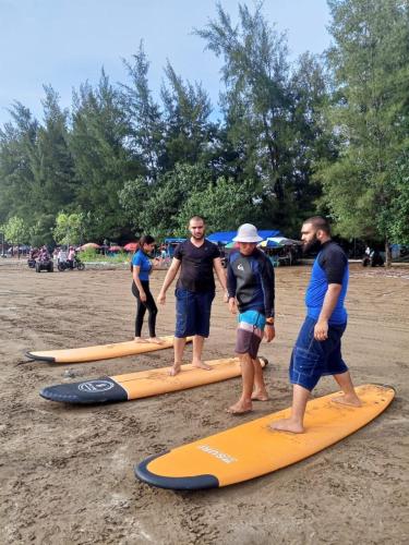 a group of people standing on surfboards on a beach at Air Manis Secret Surfcamp in Taluk Batung