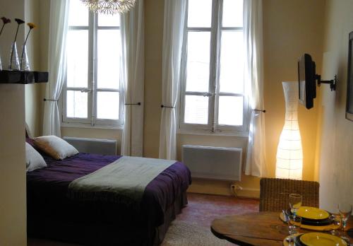a bedroom with a bed and a table and windows at Les Remparts in Avignon