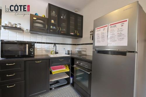 une cuisine avec un réfrigérateur en acier inoxydable et des armoires noires dans l'établissement Villa Arcade, à Carry-le-Rouet