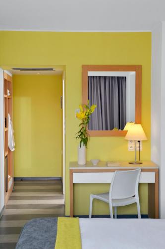 a yellow room with a desk and a chair at Airotel Galaxy in Kavala