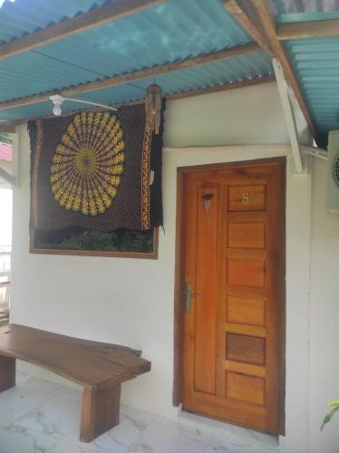 a room with a wooden door and a wooden bench at Air Manis Secret Surfcamp in Taluk Batung