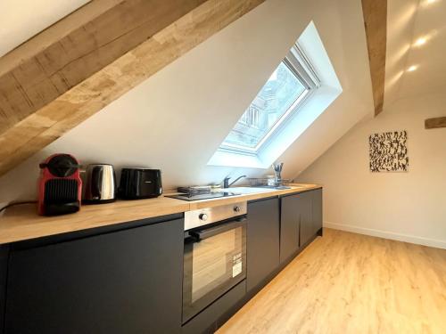 une cuisine mansardée avec un évier et une fenêtre dans l'établissement Le Grenier de la Grappe 2, à Lille