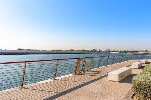 a walkway next to a body of water at Prime Location 2BR Apartment with Pool & Dining Nearby in Abu Dhabi