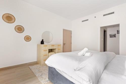 a white bedroom with a bed and a desk at Prime Location 2BR Apartment with Pool & Dining Nearby in Abu Dhabi