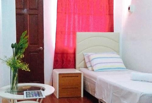 a small bedroom with a bed and a table with a laptop at RedDoorz at RHR Tourist Inn Canlaon in Kabankalan