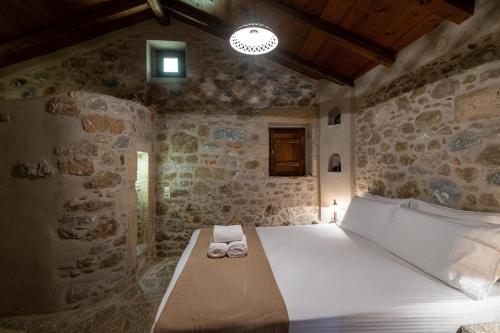 a bedroom with a bed in a stone wall at Tzokeika Traditional Settlement in Riglia