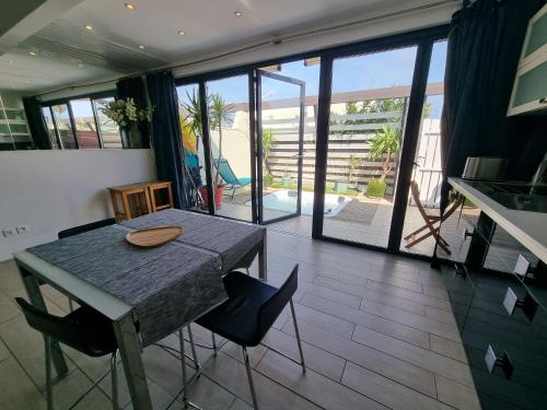 une salle à manger avec une table et des chaises et un balcon dans l'établissement Charmante Villa au Coeur du Village Naturiste, au Cap d'Agde