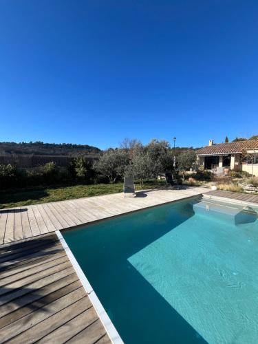 une grande piscine bleue avec une terrasse en bois dans l'établissement Le jardin secret, à Gordes