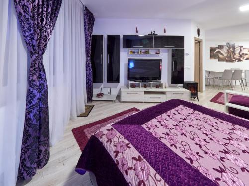 a bedroom with a purple bed and a tv at Purple Suite in Sinaia