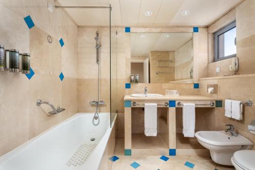 a bathroom with a tub and a sink and a toilet at Grande Real Santa Eulalia Resort & Hotel Spa in Albufeira