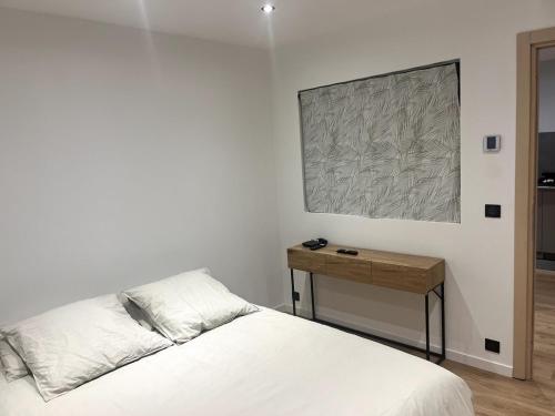 - une chambre avec un lit blanc et une table en bois dans l'établissement Appartement coeur de Cannes, à Cannes