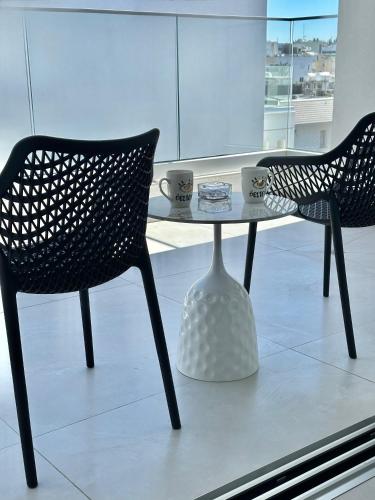two chairs and a glass table with cups on it at -Mari- Cozy Stay at Engomi Near UNIC in Nicosia