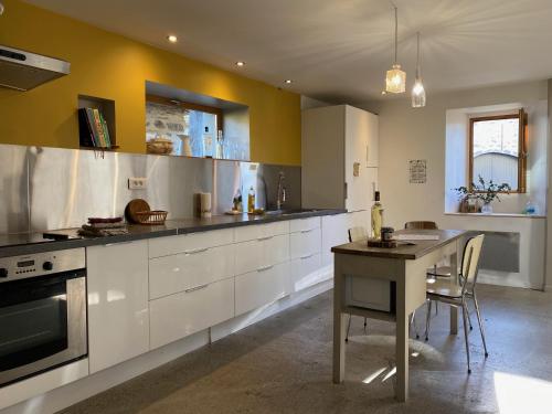 une cuisine avec des armoires blanches et une table à l'intérieur dans l'établissement Chez Castagné, à Issor