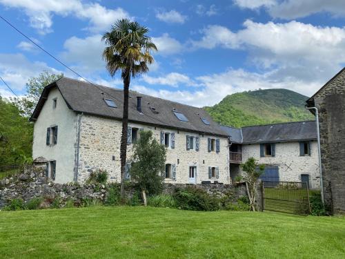 une vieille maison en pierre avec un palmier dans la cour dans l'établissement Chez Castagné, à Issor