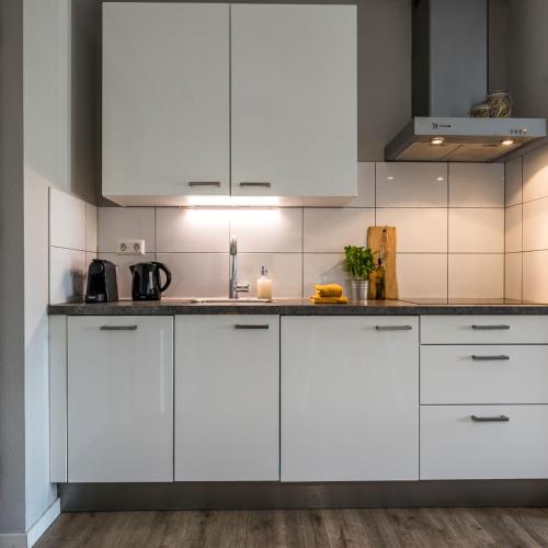 a kitchen with white cabinets and a counter top at JOINN! City Lofts Houten Utrecht in Houten