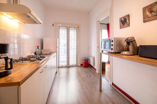 une cuisine avec des placards blancs et un comptoir avec un four micro-ondes dans l'établissement Joli T2 BAGNERES de Bigorre Centre, à Bagnères-de-Bigorre