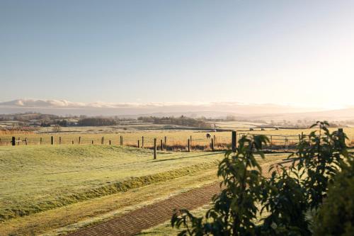a field with a fence and animals in the distance at The Retreat in Penruddock