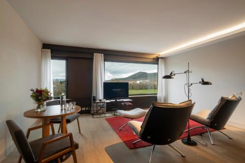 a living room with a table and chairs and a television at Eurostars Pamplona in Pamplona