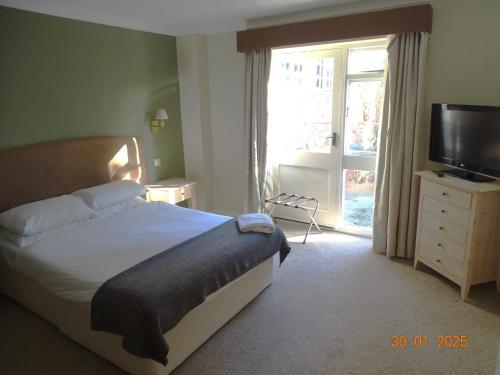 Un dormitorio con una cama y un televisor y una ventana. en Donington Manor Hotel, en Castle Donington