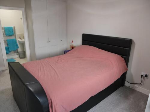 a bedroom with a black bed with a pink blanket at Cozy 2 Bedroom House in Mullingar in Mullingar