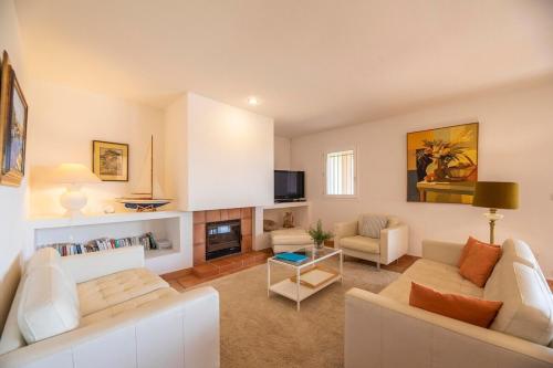 Elle comprend un salon doté d'un mobilier blanc et d'une cheminée. dans l'établissement Villa Rossa Palombaggia T4, à Porto-Vecchio