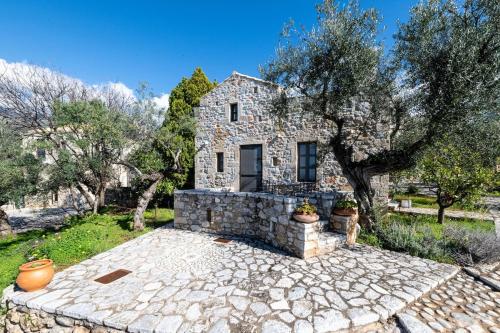 a stone house with a tree and a stone patio at Tzokeika Traditional Settlement in Riglia