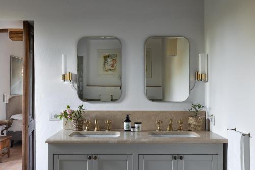 a bathroom with two sinks and two mirrors at La Fattoria del Rio di Sopra - Agriturismo Baldeschi in Tuoro sul Trasimeno