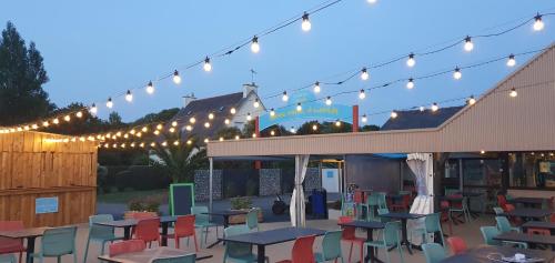 un patio avec des tables et des chaises sous une chaîne de lumières dans l'établissement Camping Paradis Bellevue, à Erquy