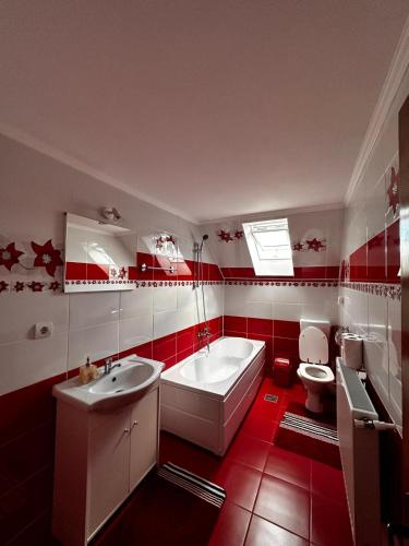 un bagno rosso e bianco con vasca e WC di Dor de munte a Măgura