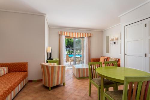 a living room with a green table and chairs at Grande Real Santa Eulalia Resort & Hotel Spa in Albufeira