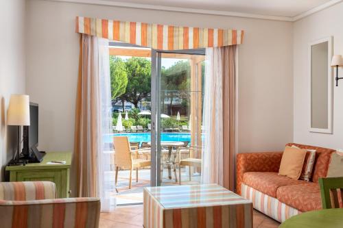 a living room with a couch and a sliding glass door at Grande Real Santa Eulalia Resort & Hotel Spa in Albufeira