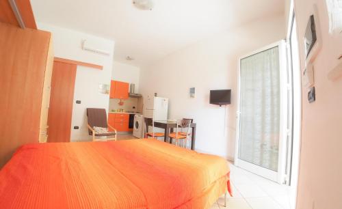 a bedroom with an orange bed and a kitchen at Imperatrice Rent Room - Porto Cesareo in Torre Squillace