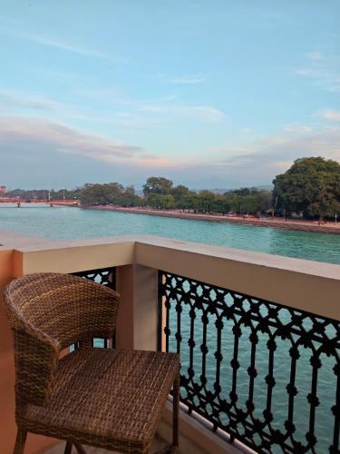a chair sitting on a balcony overlooking the water at Gauri Gangaa in Haridwār