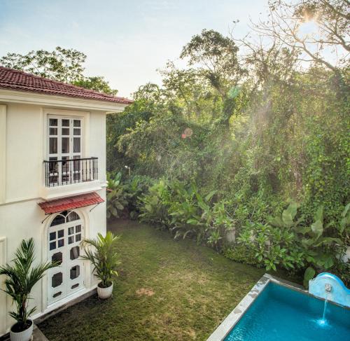 a backyard with a swimming pool next to a house at LohonoStays Calisto Villa C in Siolim