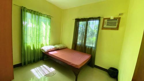 ein kleines Zimmer mit einem Bett in der Ecke eines Zimmers in der Unterkunft Colorful Tropical Bungalow in Bacong