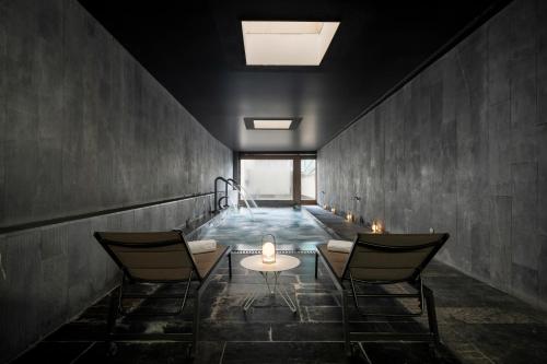 a room with a pool with two chairs and a table at Eurostars Pamplona in Pamplona