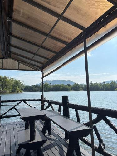a picnic table and chairs on a dock next to the water at บ้านต้นรักษ์ BanTonRuk Takuapa in Takua Pa