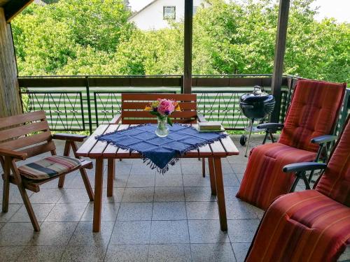 a table with a vase of flowers on a patio at Ferienwohnung Rhönnest mit großer überdachter Terrasse in Schönau an der Brend