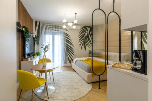 a bedroom with a bed and a table and yellow chairs at AIASTAY Bucharest River Apartments in Bucharest