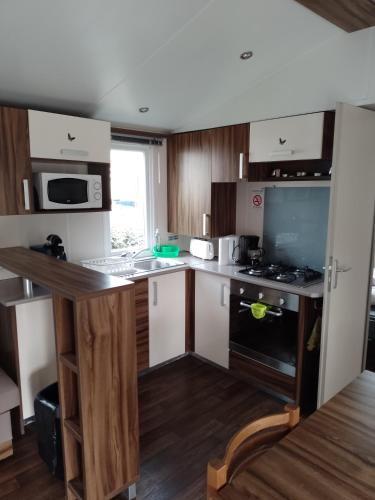 a kitchen with wooden cabinets and a counter top at MHVACANCES LOUENT PLUSIEURS MOBILHOMES DANS CAMPING 4 ETOILES PROCHE CHATEAUX et ZOO BEAUVAL in Onzain