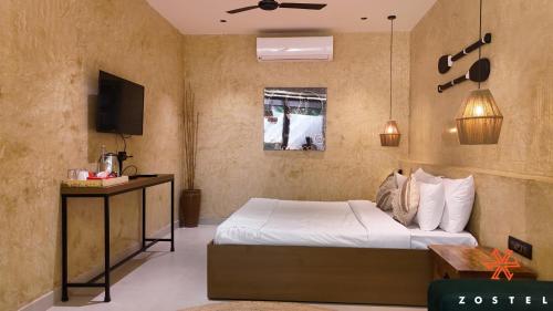 a bedroom with a bed and a television in a room at Zostel Goa, Morjim in Morjim