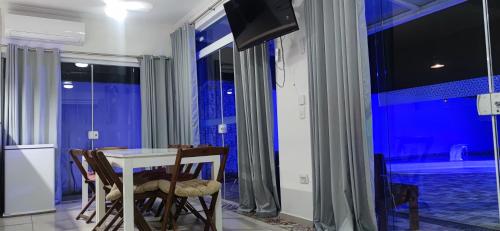une salle à manger avec une table et des chaises et une télévision dans l'établissement Casa de Praia em Bertioga, São Paulocom Piscina Ar Condicionado Wifi a 500m do Mar, à Bertioga